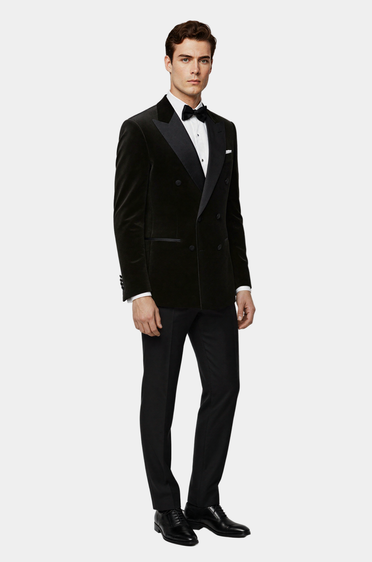 Man wearing a black tuxedo with a white shirt and black bow tie on a light gray background